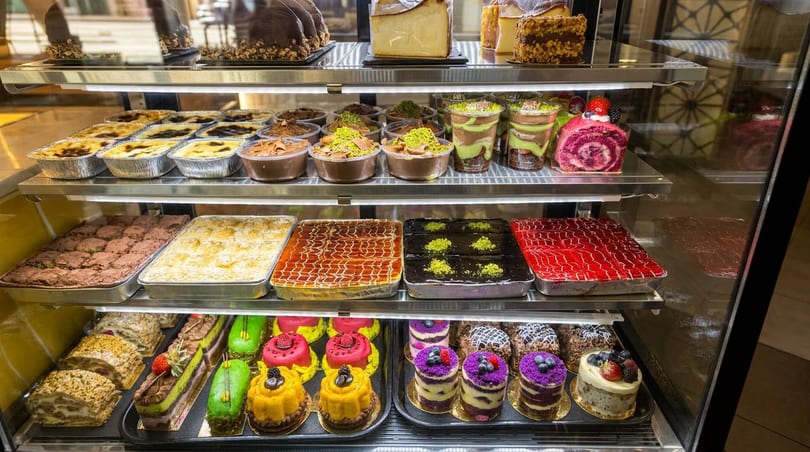 A brightly lit display case filled with a wide variety of colorful desserts and pastries.