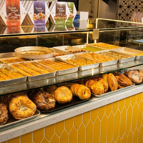 A brightly lit display case filled with various Turkish delights, baklava, and pastries.